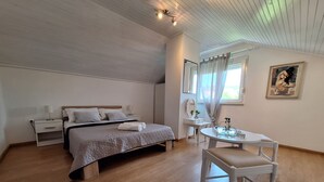 Une chambre à coucher comprenant un lit, des tables de chevet, un bureau, une chaise, un miroir et une fenêtre avec des rideaux.