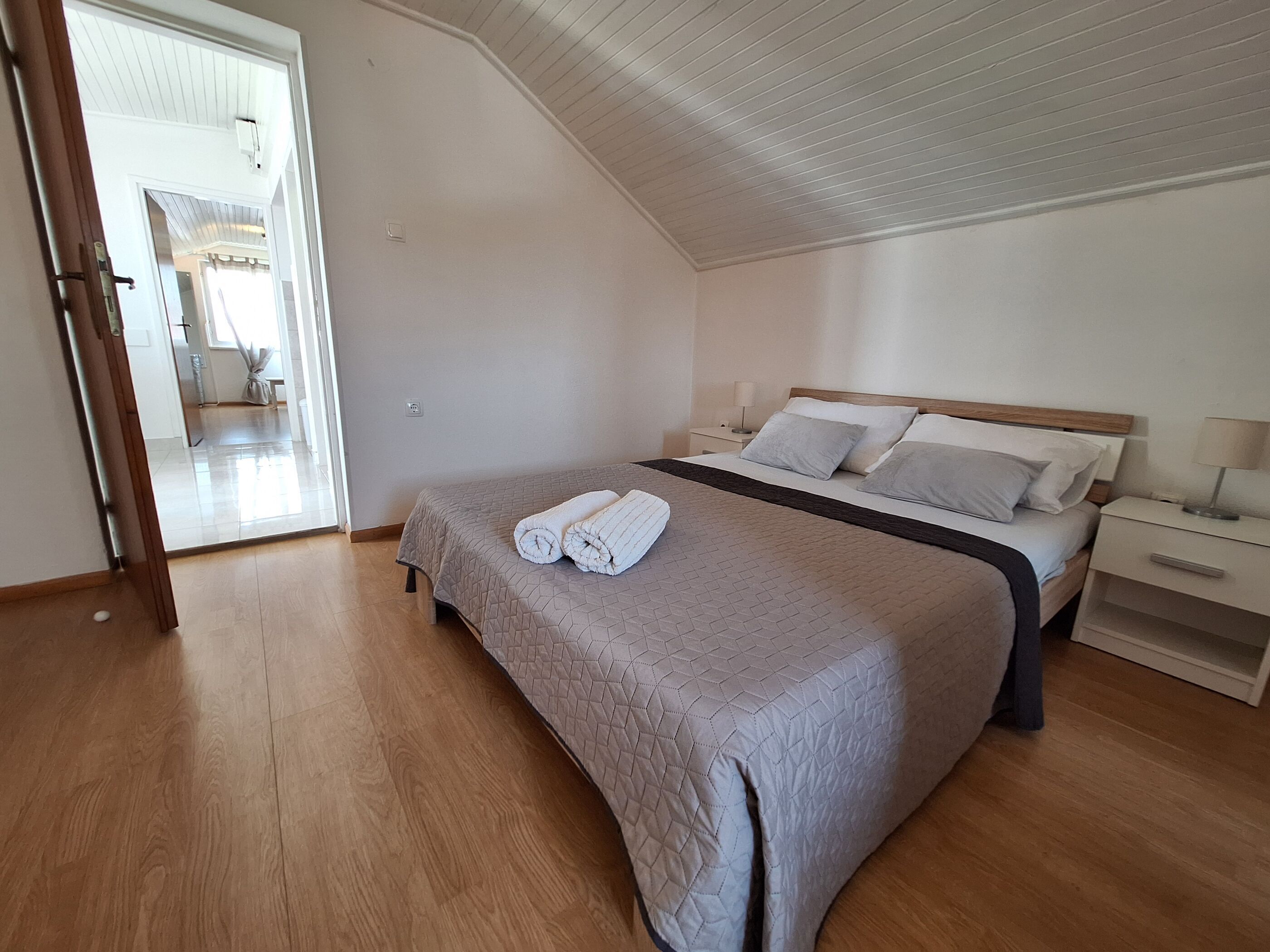 A bedroom with a bed, bedside tables, and a wooden floor.