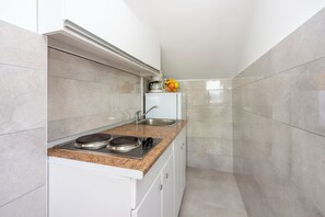 A compact kitchen with a built-in stove, a sink, and a small refrigerator. - Apartments Marmar (Crikvenica)