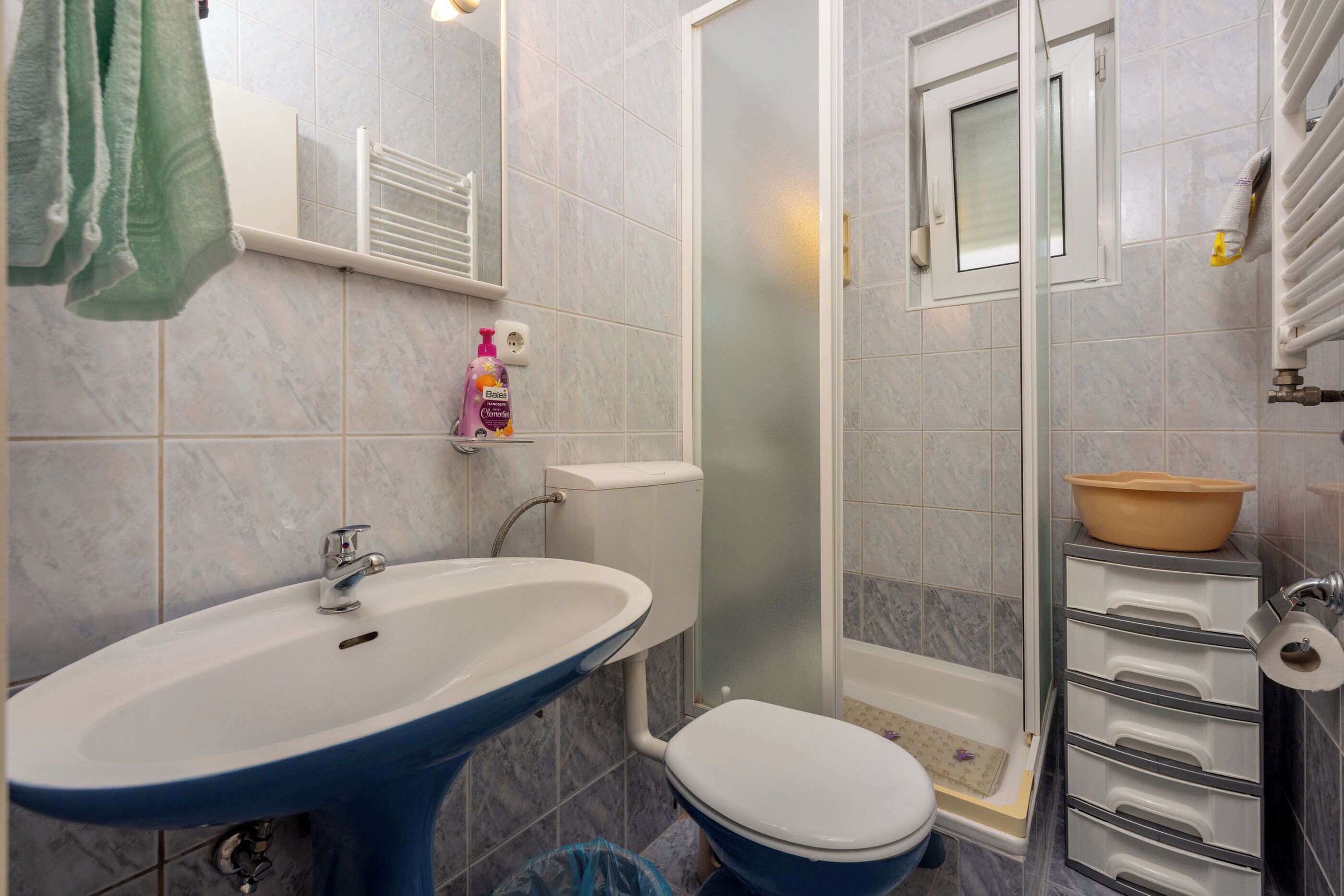 A bathroom with a blue sink, white toilet, and a glass-enclosed shower area.