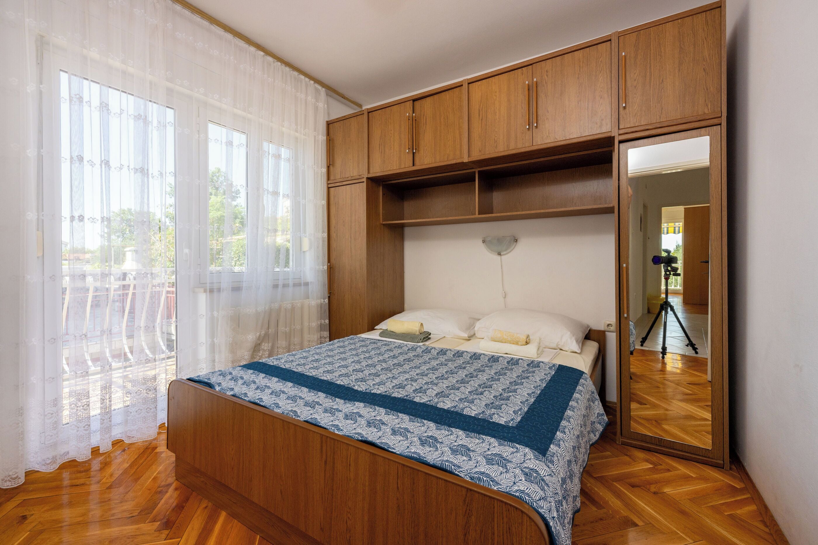 A bedroom with a wooden bed, a large mirror, and a wardrobe.
