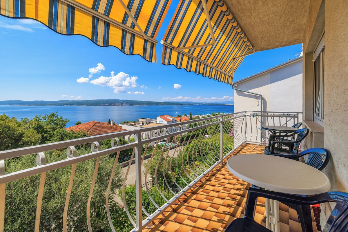 Ein Balkon mit Meerblick, einem Tisch und Stühlen.