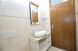 A bathroom with a white sink, a mirror, and a wooden door. - Apartments Ljubomir (Cres)