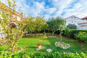 A well-maintained garden with a variety of trees and shrubs, a small pond, and a stone pathway. - Apartments Dolores (Rab)