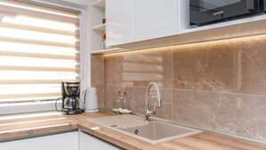 A modern kitchen with a built-in microwave, a coffee maker, and a sink with a marble backsplash. - Apartment Nela (Trogir)