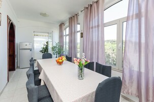 Un comedor con una mesa preparada para cuatro personas, un refrigerador y vistas a zonas verdes.