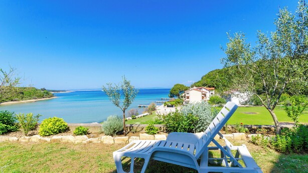 A view of a coastal area with a clear blue sky, a body of water, and a building with a red roof. - Apartments Katica (Rab)