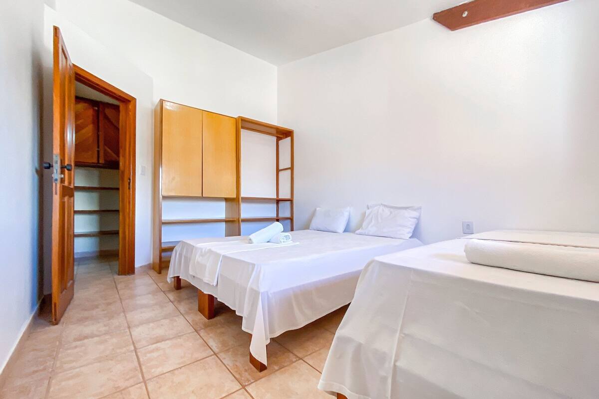 A bedroom with two beds, a wardrobe, and a door leading to a hallway.