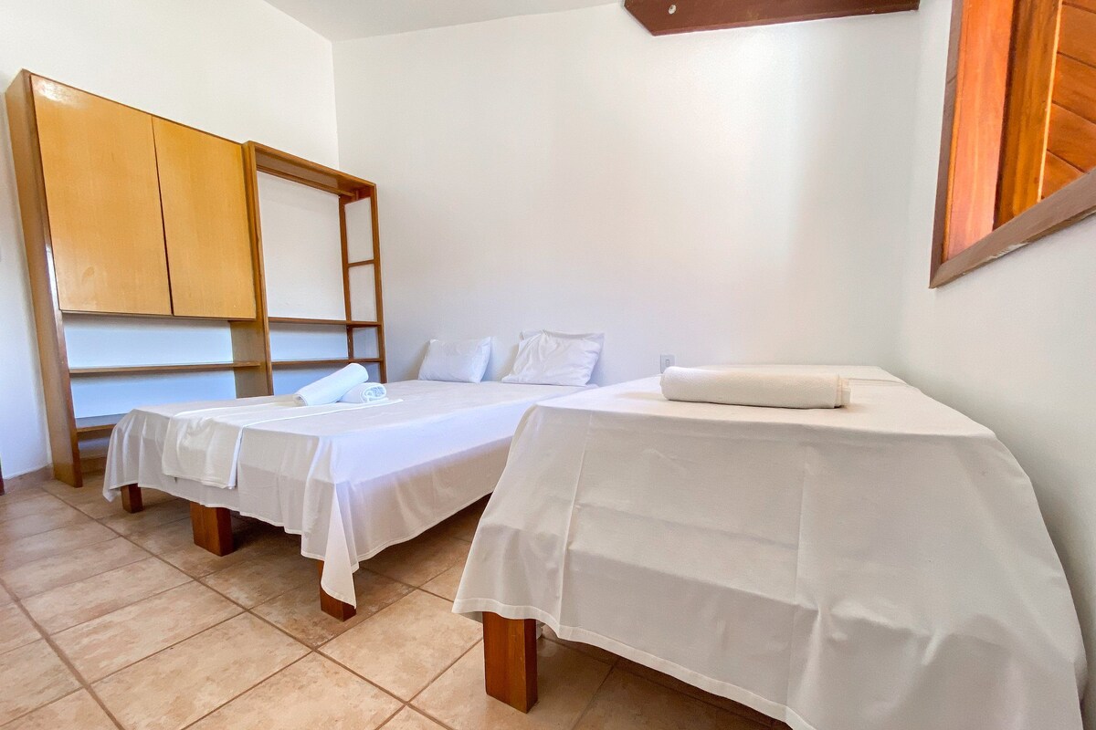 A hotel room with two single beds, a wooden wardrobe, and a tiled floor.