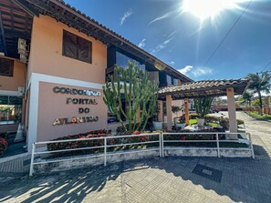 A building with a sign reading 'CORDOMINO PORTAL DO ATLÁNTICO' and a cactus in front. - Condomínio Portal do Atlântico (Porto Seguro)