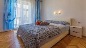 Quarto com cama, mesa de cabeceira e luminária na parede.