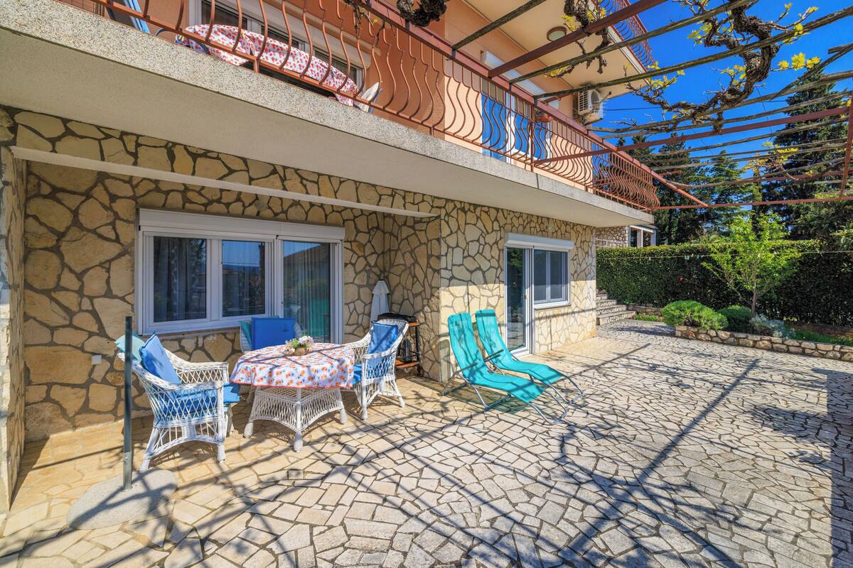 A stone house with a balcony, outdoor seating, and a garden.