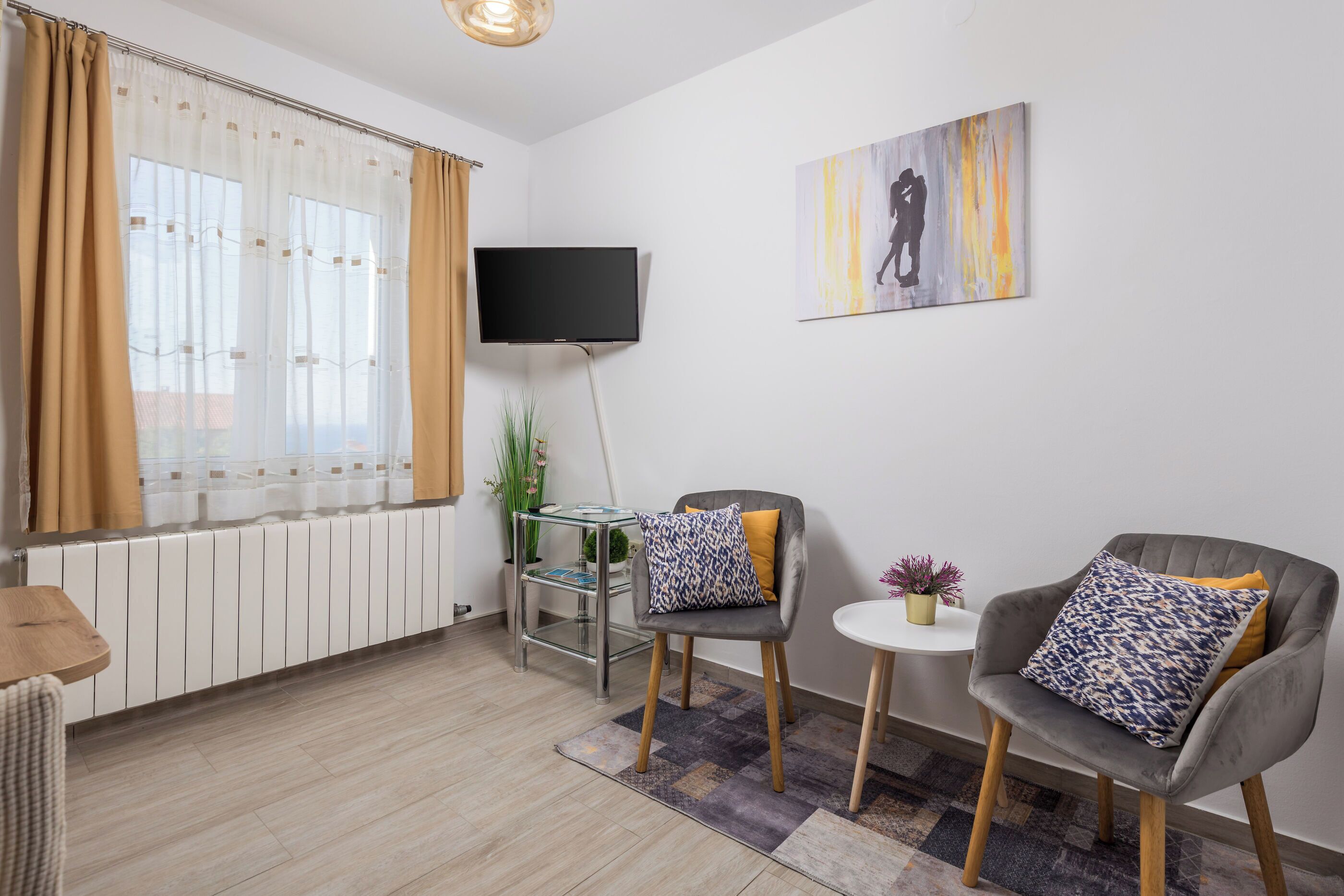 A modern living room with a sofa, a small table, a TV, and a window with curtains.