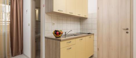 Una cocina compacta con armarios de madera, un lavamanos y un frutero sobre la encimera.