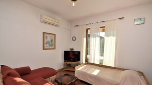 A room with a bed, a sofa, a TV, and a window with curtains. - Apartments Boris (Umag)
