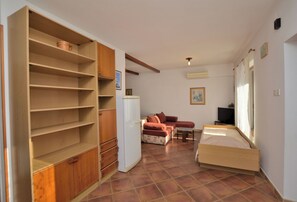 A compact room with a bed, a sofa, a TV, and a kitchen area with cabinets and a refrigerator. - Apartments Boris (Umag)