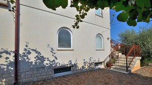 A building with a stone-paved courtyard, two arched windows, and a staircase with metal railings. - Apartments Boris (Umag)
