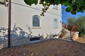 A building with a stone-paved courtyard, two arched windows, and a staircase with metal railings. - Apartments Boris (Umag)