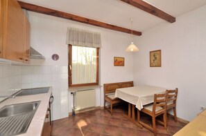Una cucina con finestra, termosifone, lavello e tavolo con sedie.