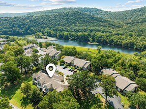 A residential area with multiple houses, a river, and a forested hill in the background. - Pointe Royale | 3 Kings | Garage | No-Step Entry (Branson)