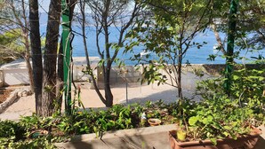 Une vue d’une zone côtière avec des arbres, une plage et des bateaux au loin.