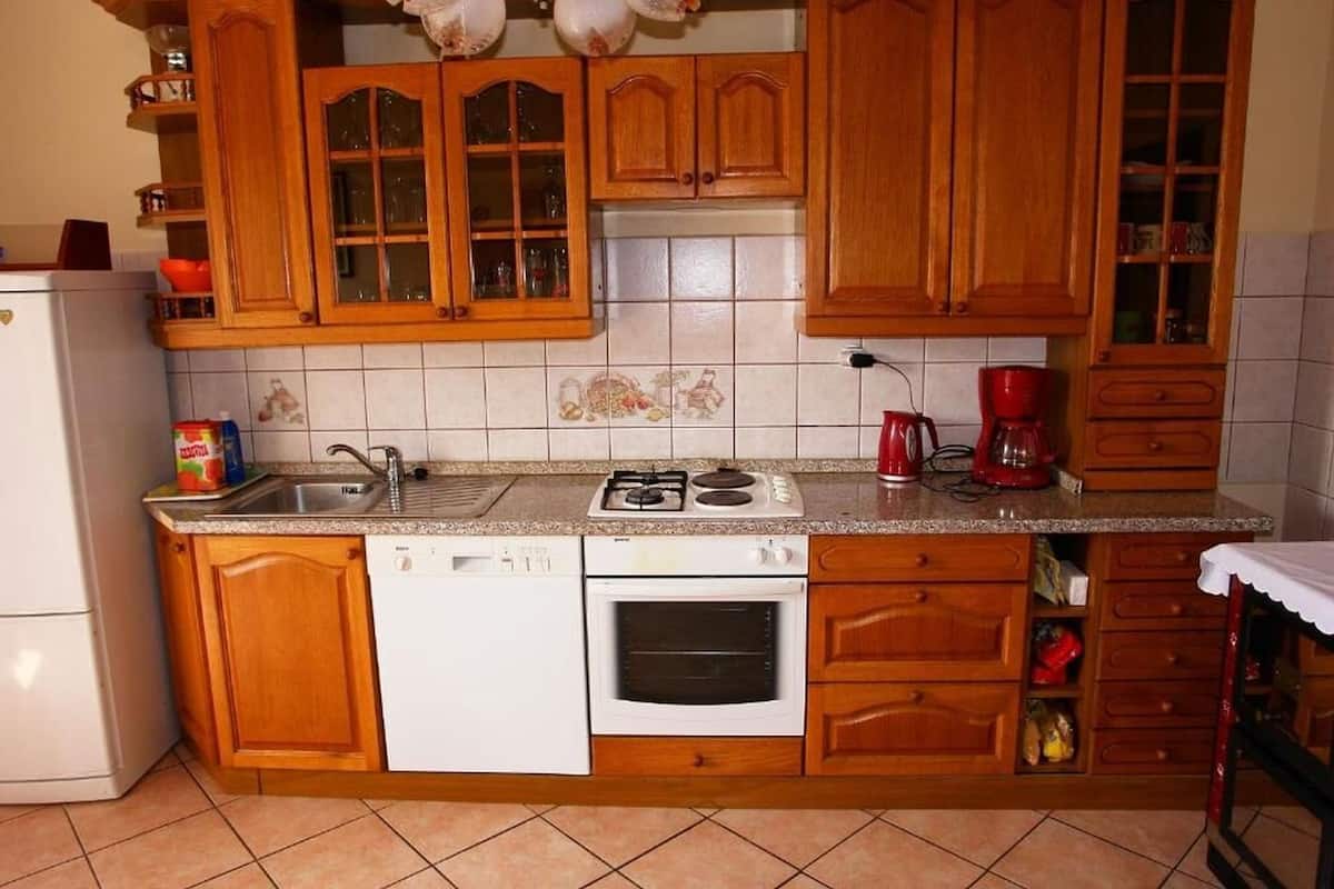 A kitchen with wooden cabinets, a sink, a stove, and a dishwasher.