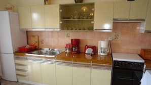 A kitchen with a refrigerator, double sink, red coffee maker, and a dishwasher. - Apartments Nikolina (Novi Vinodolski)