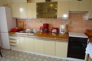 A kitchen with a refrigerator, double sink, red coffee maker, and a dishwasher. - Apartments Nikolina (Novi Vinodolski)