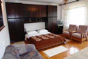 A bedroom with a bed, a TV, a wardrobe, and two chairs. - Apartments Nikolina (Novi Vinodolski)