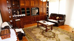 A traditional living room with a wooden cabinet, a sofa, a coffee table, and a patterned rug. - Apartments Nikolina (Novi Vinodolski)