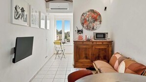 A living room with a flat-screen TV, a wooden cabinet, a couch, and a dining area with a chair. - Discover your oasis of relaxation in Pitelli, a charming village overlooking the sea! We present you a splendid holiday home ideal for families and groups of up to 4 people.The house consists of two welcoming and tastefully furnished bedrooms, perfect fo (Pitelli)