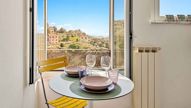 A balcony with a table set for two, a chair, and a view of a hillside town. - Discover your oasis of relaxation in Pitelli, a charming village overlooking the sea! We present you a splendid holiday home ideal for families and groups of up to 4 people.The house consists of two welcoming and tastefully furnished bedrooms, perfect fo (Pitelli)