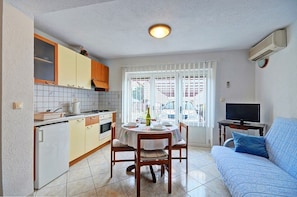 A compact kitchen with a dining table, a sofa, and a TV. - Apartments Marica (Pula)