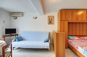 A compact room with a sofa, a bed, a TV, and a wooden cabinet. - Apartments Marica (Pula)