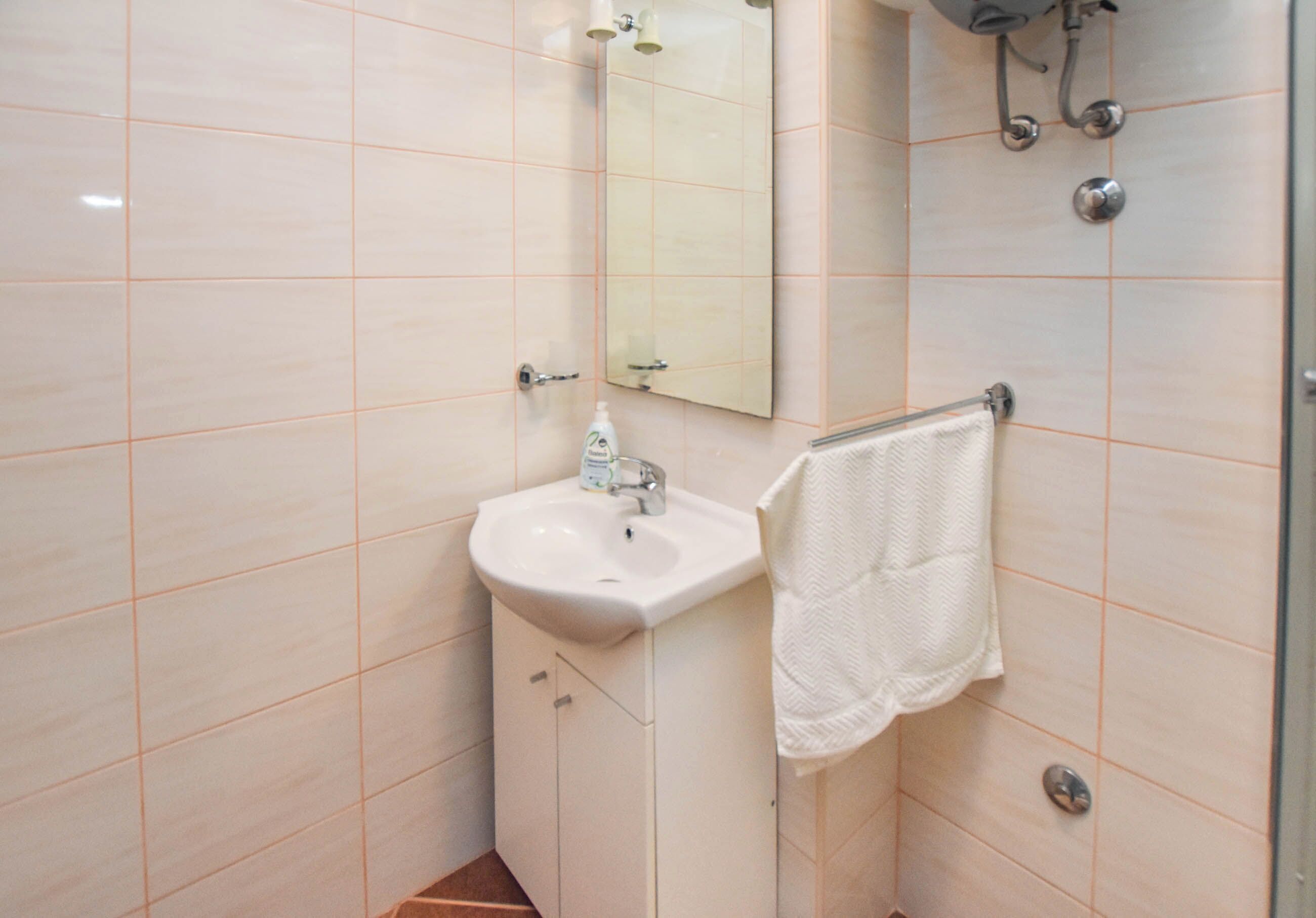 A bathroom with a sink, mirror, and towel rack.