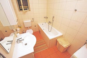 Ein Badezimmer mit Waschbecken, Toilette, Badewanne und Mülleimer.