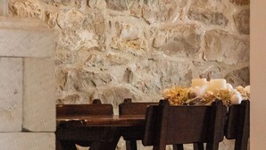 A stone wall with a framed map, a wooden table with chairs, and a candle arrangement. - House Ston (Orebic)