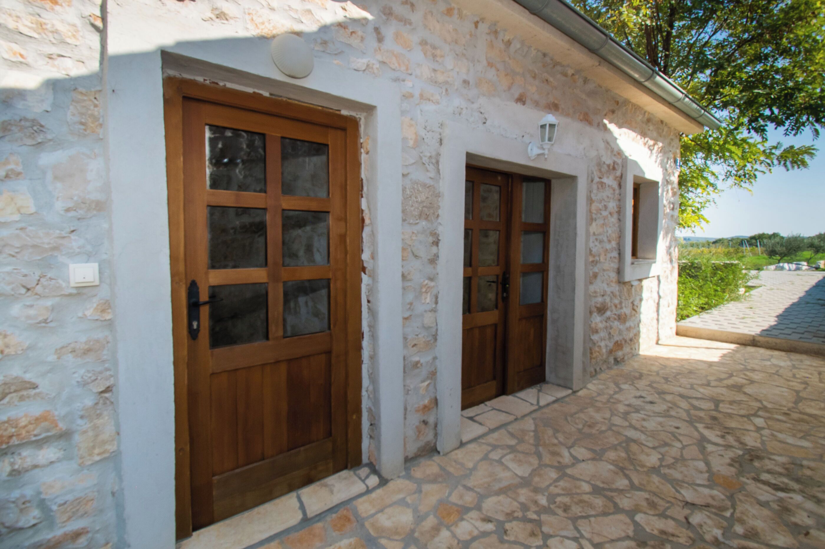 A stone building with two wooden doors and a small window.