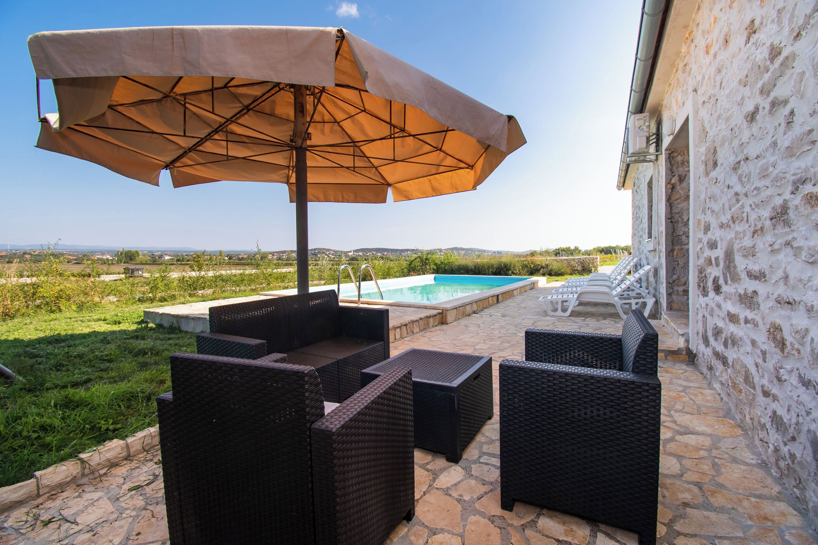 Un patio con mobili in vimini e una piscina.