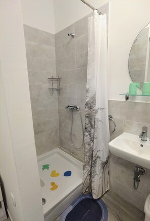 Ett badrum med dusch, handfat och toalett.