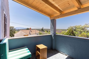 A balcony with a wooden ceiling, a green-striped bench, and a small wooden table. - Apartment Lumanera Stivan (Cres)