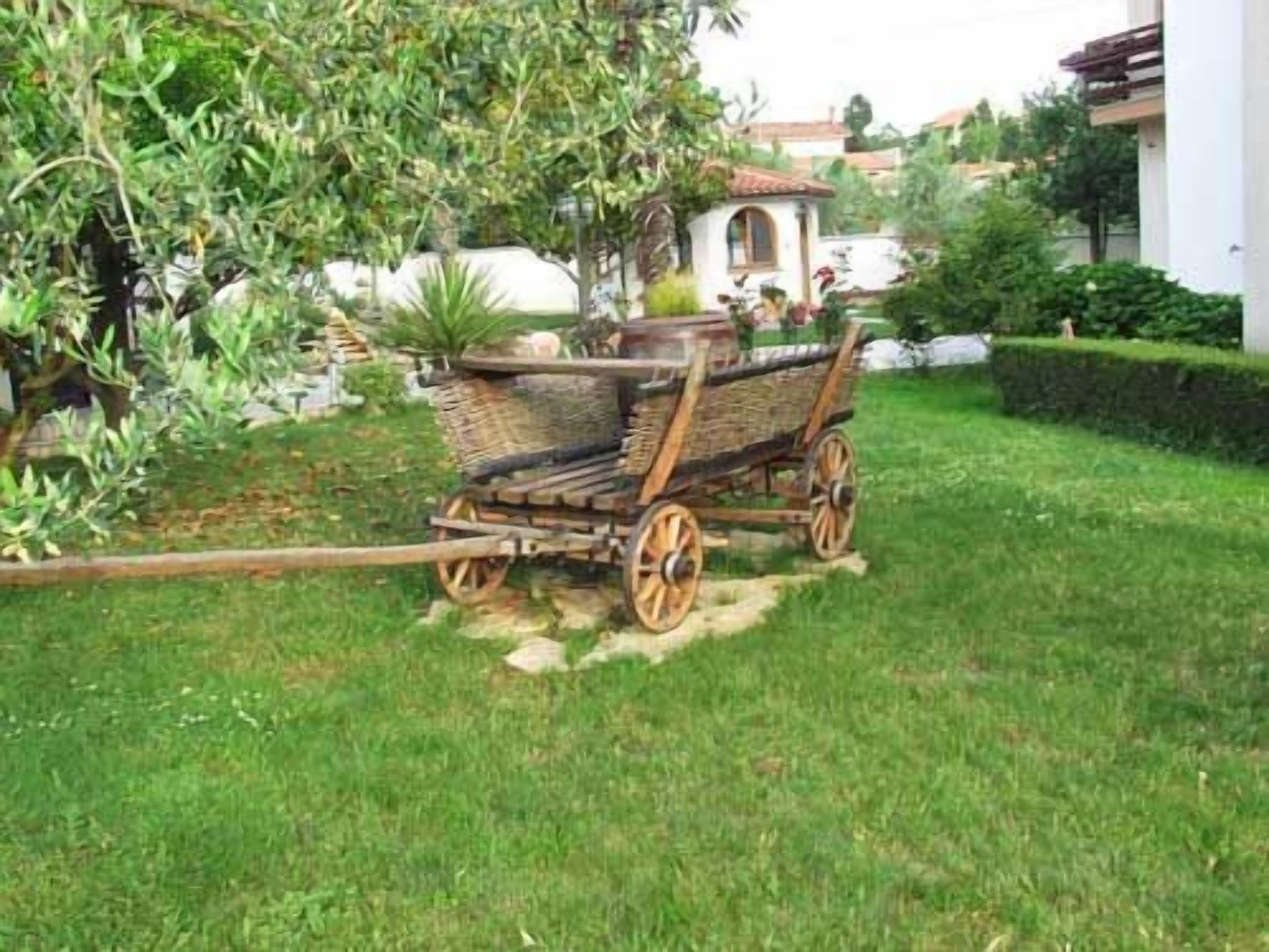A garden with a wooden cart and a small building in the background.