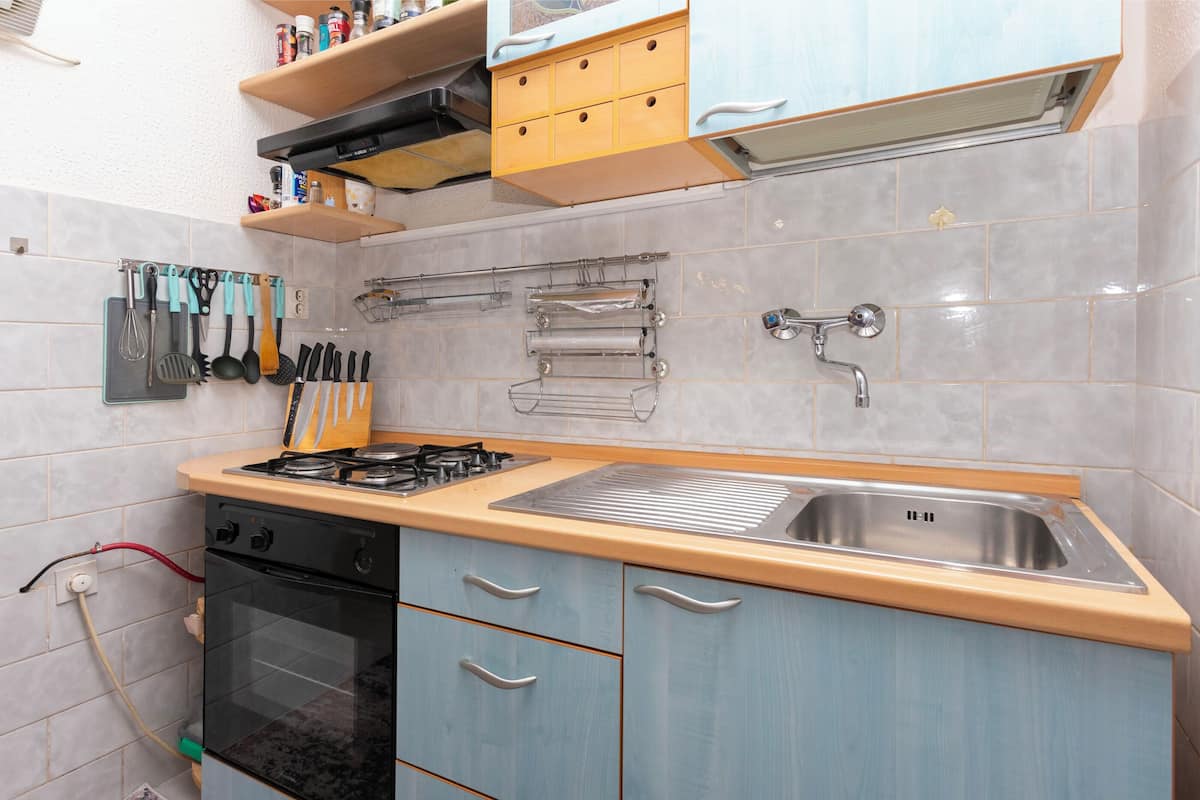 A kitchen with a gas stove, sink, and various utensils.