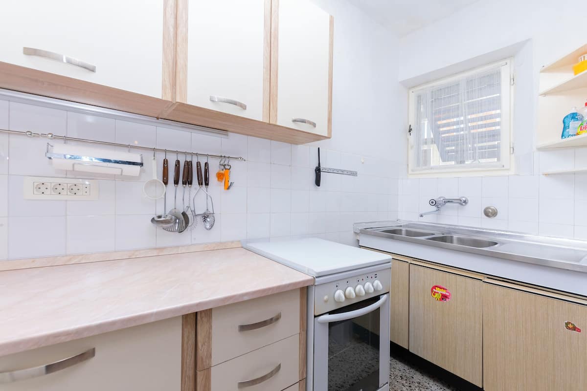A kitchen with white cabinets, a countertop, a sink, and a window.