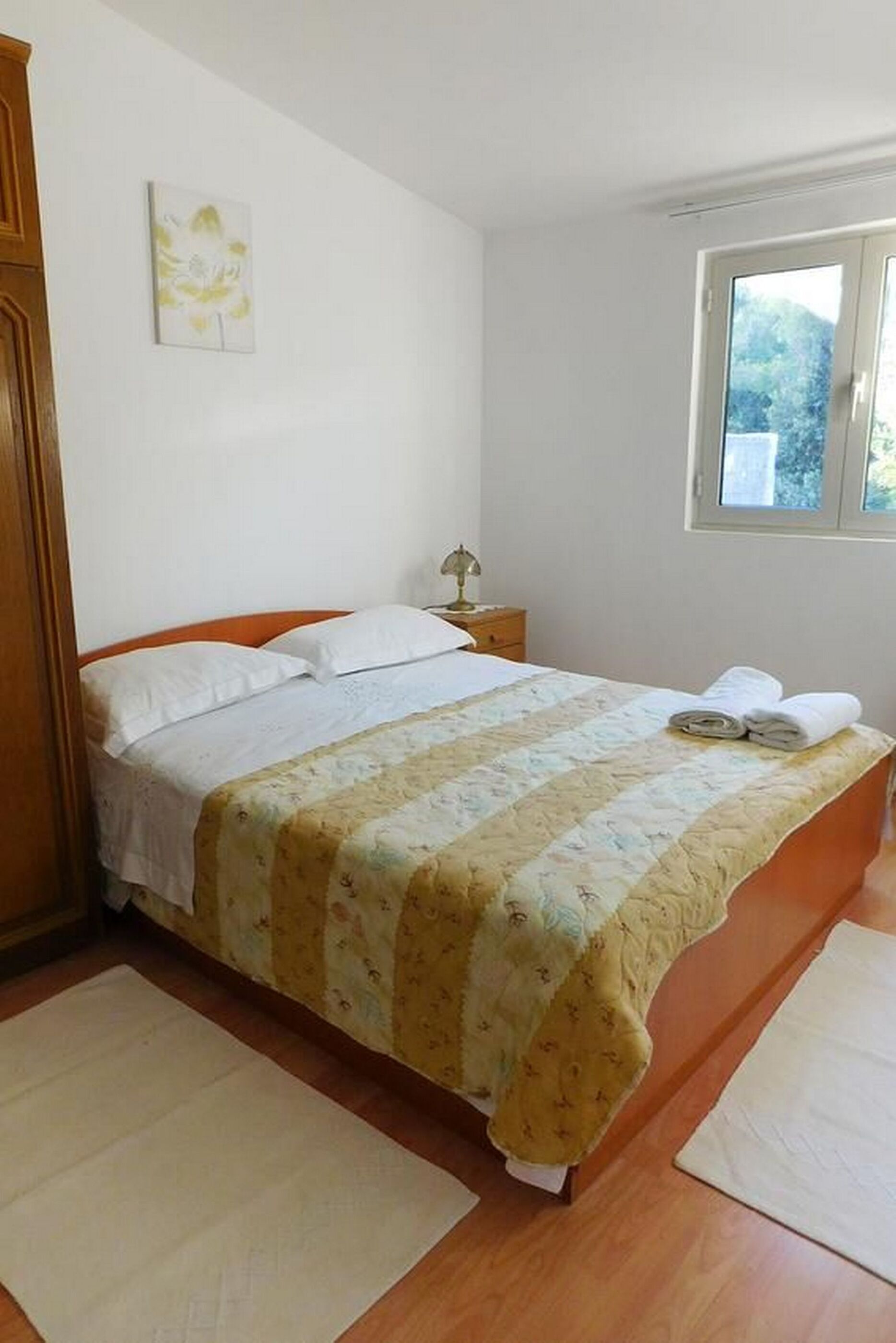 Quarto com cama, mesa de cabeceira, janela e porta.