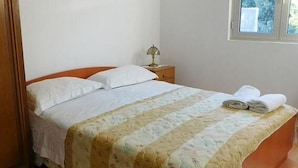 Ένα υπνοδωμάτιο με ένα κρεβάτι, ένα κομοδίνο, ένα παράθυρο και μια πόρτα.