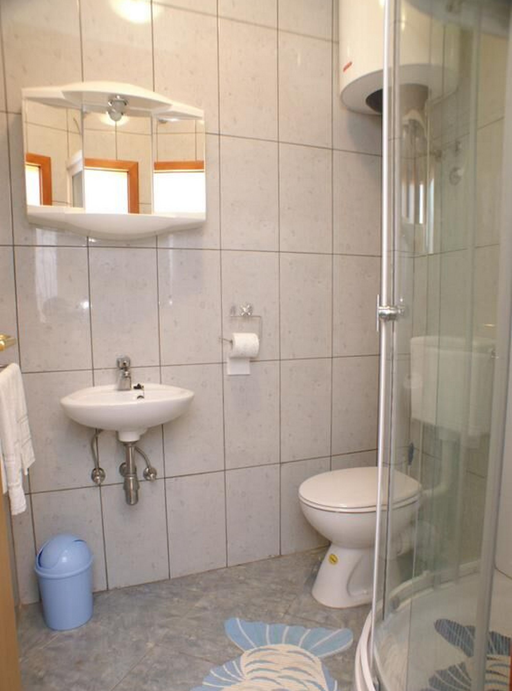 Un baño con lavamanos, inodoro y cabina de ducha de vidrio.