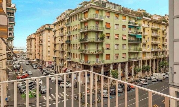 Un edificio residencial de varios pisos con balcones, estacionamiento y vista a la calle.