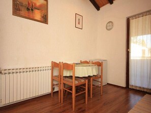 A dining area with a table and chairs, a radiator, a clock, and a painting on the wall. - Apartments Matohanac (Fazana)