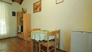 A dining area with a table, chairs, a refrigerator, and a cabinet. - Apartments Matohanac (Fazana)